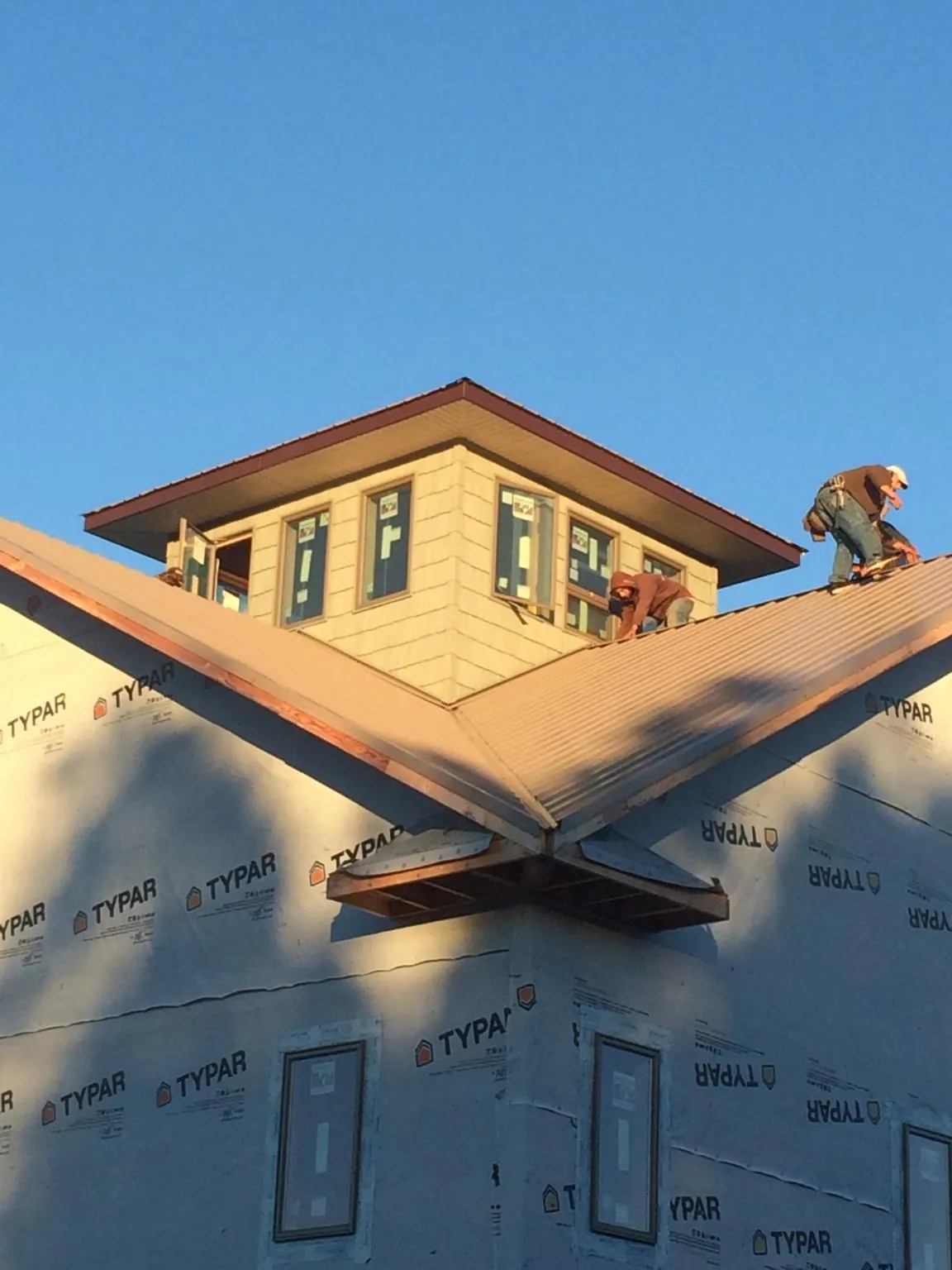 Roofers working around a rooftop cupola on a new metal roof at sunset — Roof Waterproofing in Hyde Park by Roofing Brothers